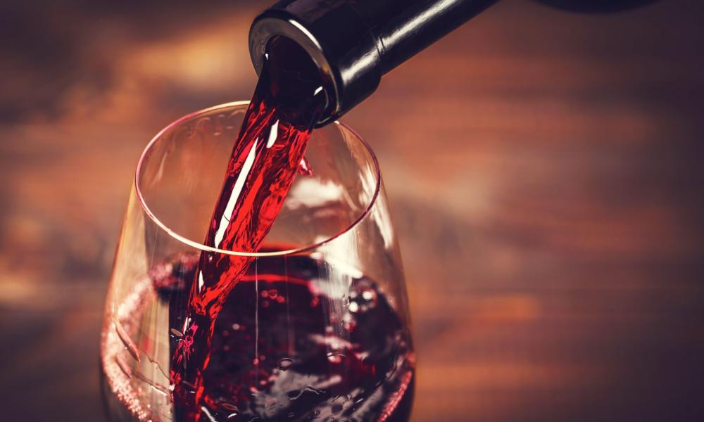 Vino rosso versato in calice, evocando calore e raffinatezza.