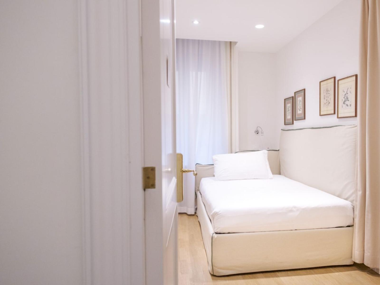 Camera accogliente e luminosa con letto singolo e quadri alle pareti.