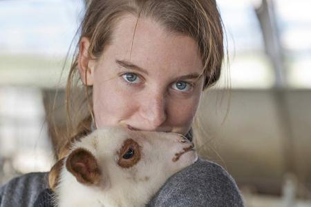 Giovane donna abbraccia teneramente un agnello, trasmettendo amore e calore.