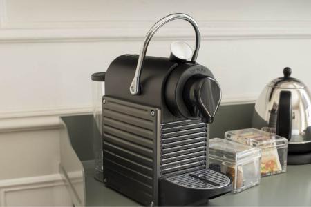 Macchina da caffè elegante su bancone, accanto a bollitore e scatole di tè.