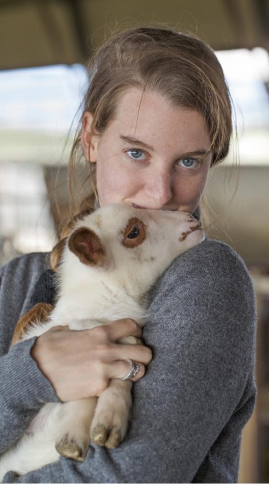 Giovane donna abbraccia teneramente un agnello, trasmettendo amore e dolcezza.