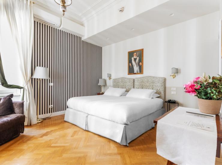 Camera elegante con letto matrimoniale, pavimento in legno e piante rigogliose.