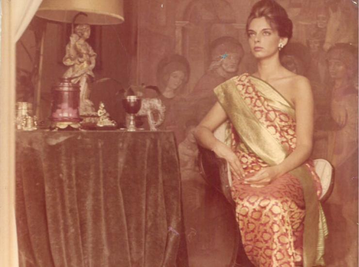 Donna elegante in sari, atmosfera vintage, tavolo con oggetti decorativi.