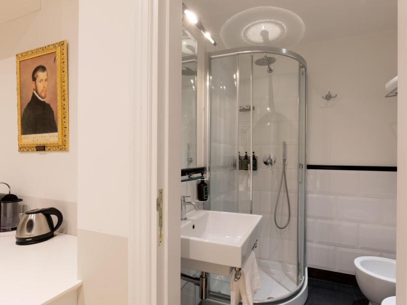 Bagno moderno con doccia elegante e un quadro storico accanto a un bollitore.