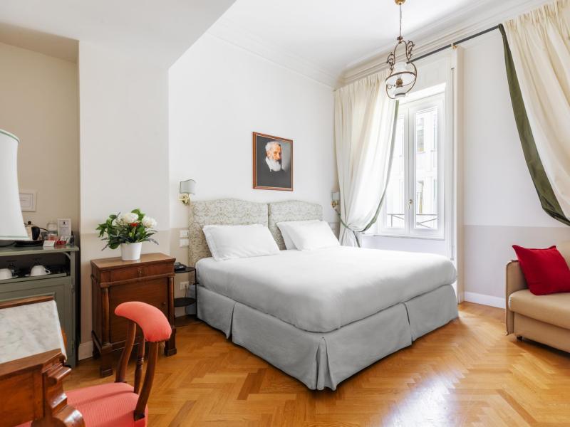 Camera elegante con letto matrimoniale, tende bianche, atmosfera accogliente e luminosa.