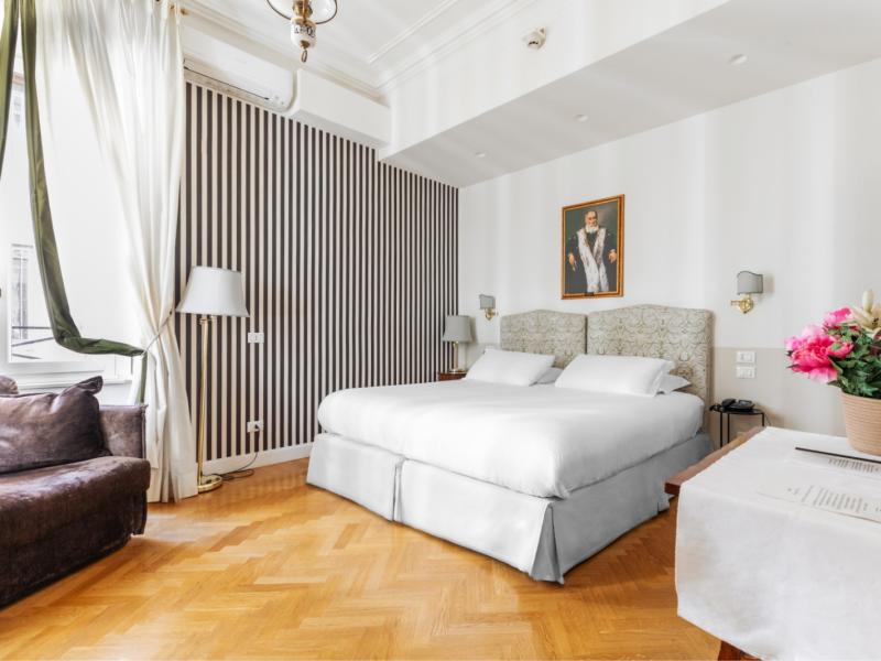 Camera elegante con letto matrimoniale, parquet lucido e decorazioni floreali.