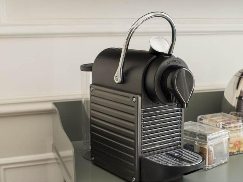 Macchina da caffè elegante su bancone, accanto a bollitore e scatole di tè.