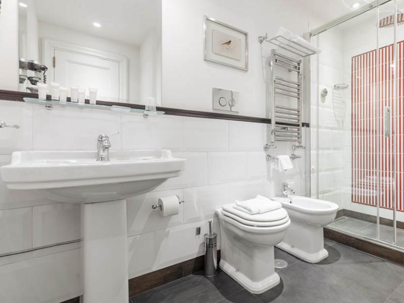 Bagno moderno, luminoso e accogliente, con doccia elegante e piastrelle rosse vivaci.