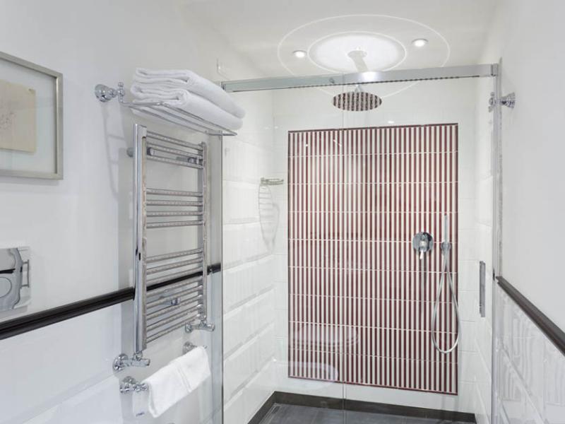 Elegante doccia moderna con piastrelle a righe e soffione circolare, atmosfera minimalista e pulita.