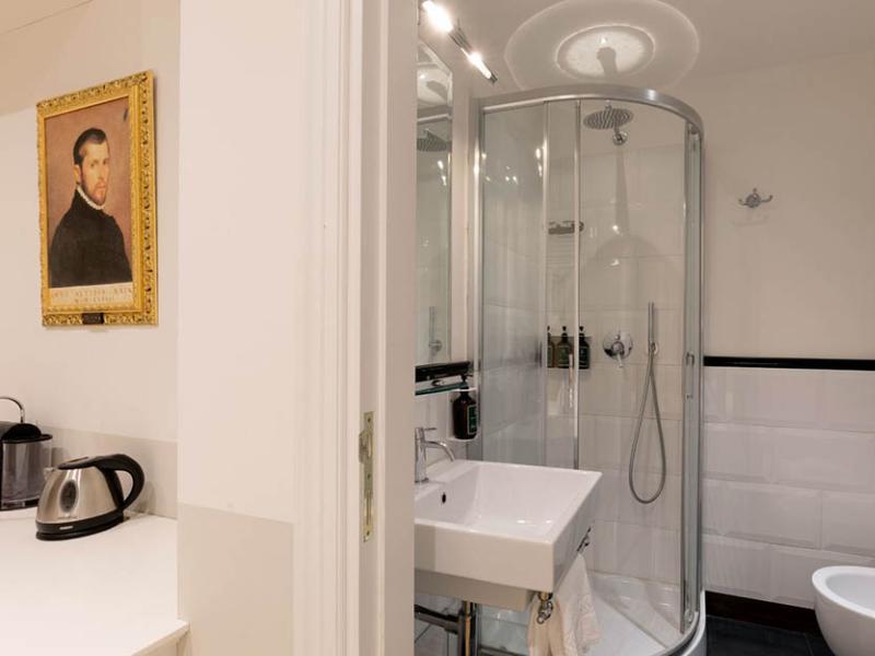 Bagno elegante con doccia moderna e ritratto classico, atmosfera sofisticata e accogliente.