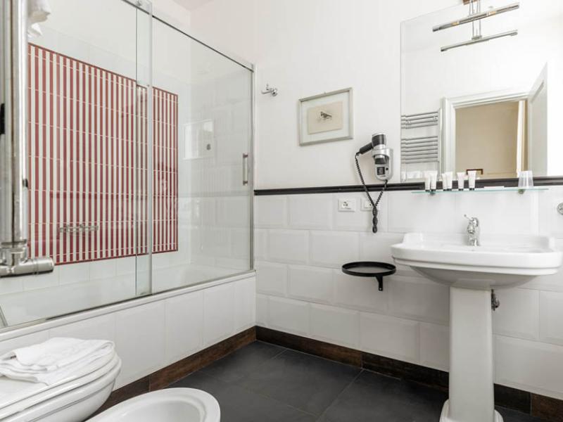 Bagno elegante con doccia moderna e dettagli rossi, atmosfera pulita e luminosa.