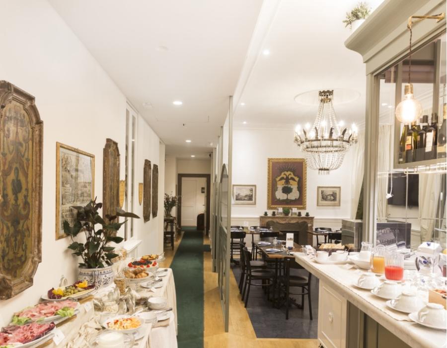 Elegante sala colazioni con buffet ricco di cibi freschi e lampadario scintillante.